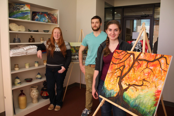 Arts Ink is opening for business. The student-run art gallery in Myles Center for the Arts serves as a real world experience in entrepreneurship and making a living as an artist. Displaying some of the works are, from left, senior Julia Tenney, junior Duncan Lint and junior Nicola Merriman. 