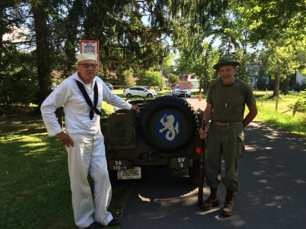 Daniel and Bill with a Jeep that has the logo of the 59th Coastal Artillery unit painted on the back