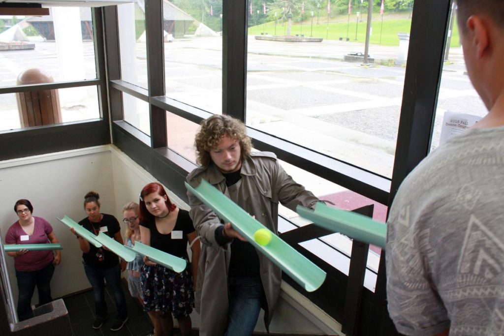 Photo Caption: New students participate in a team building exercise in which they balance a tennis ball in plastic tubing and then pass the ball on to the next person in their group. The activity was part of the “Write Your Story” initiative.